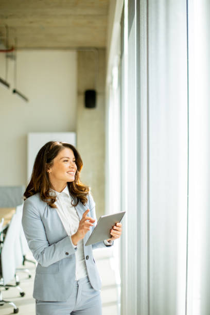 istock Young woman working on digital tablet by the office window 1500623382