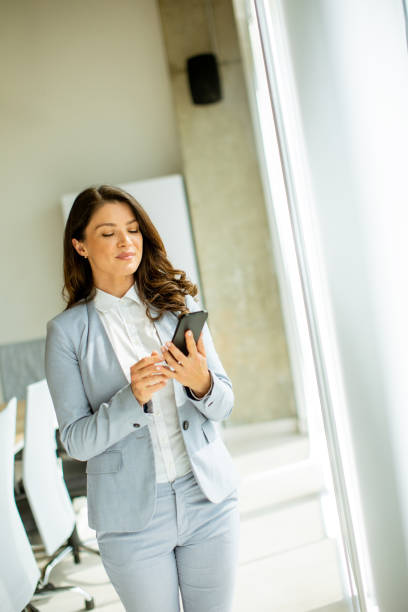 istock Young woman using mobile phone by the office window 1500623394