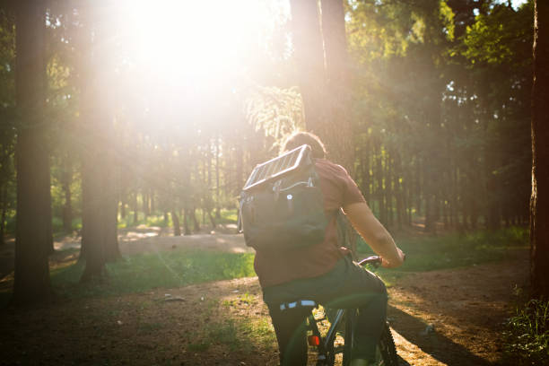 istock Man with portable solar battery on his backpack to charge smartphone in nature while riding bicycle. Sustainable lifestyle, ecological alternative energy and ecology concepts. 1500624491