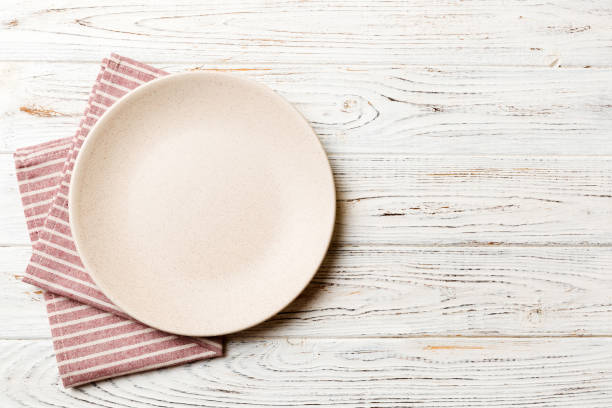 istock Top view on colored background empty round white plate on tablecloth for food. Empty dish on napkin with space for your design 1500627623