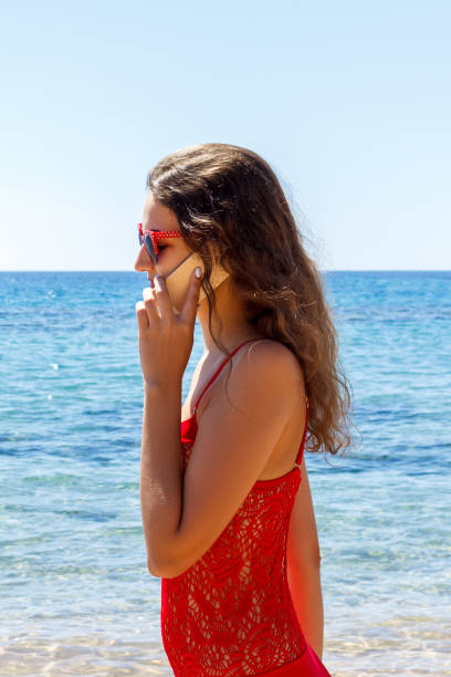 istock young smiling woman talking by phone on a beach 1500627644