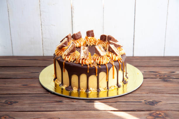 Gorgeous snickers cake with peanut butter cream, melted chocolate, candy bars and salted caramel