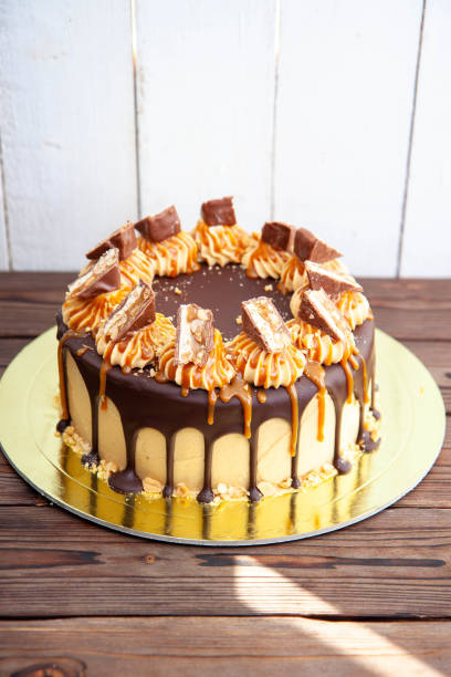 Gorgeous snickers cake with peanut butter cream, melted chocolate, candy bars and salted caramel