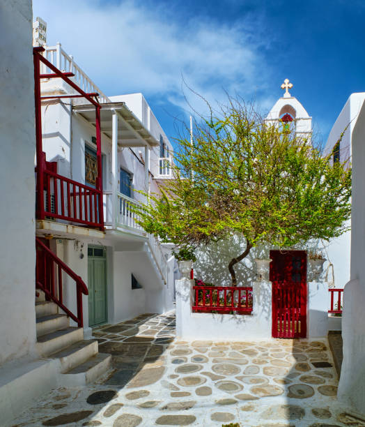 美しい伝統的な狭い石畳の通り、ギリシャの島の町の小さな広場。白塗りの家。小さな礼拝堂とオリーブの木。ミコノス島、ギリシャ。 - door greek culture doorway church ストックフォトと画像
