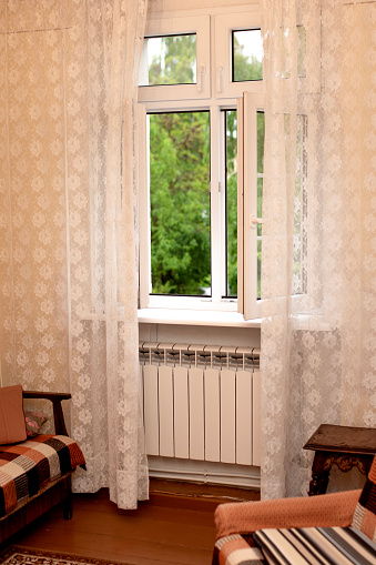 Open window in an old house with white 
lace curtains.