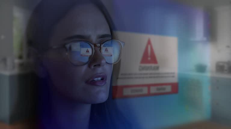 Computer screen virus warning symbol, close up. Woman wearing spectacles with screen reflecting.