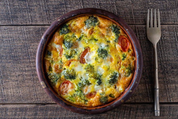 istock Ceramic bowl with vegetable frittata, simple vegetarian food. Frittata with egg, tomato, pepper, onion, broccoli and cheese on wooden table. Italian egg omelette 1500631767