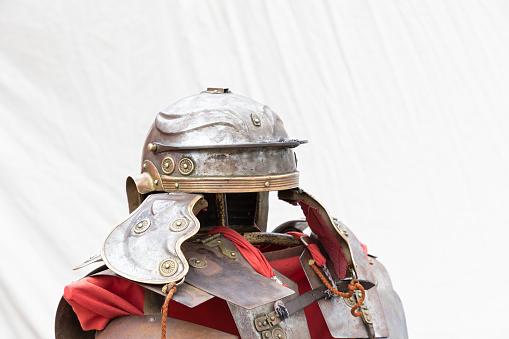 horizontal view in foreground of an exhibitor with armor and imperial helmet of a soldier from ancient roman empire, lorica segmentata and galea of a roman legionary soldier