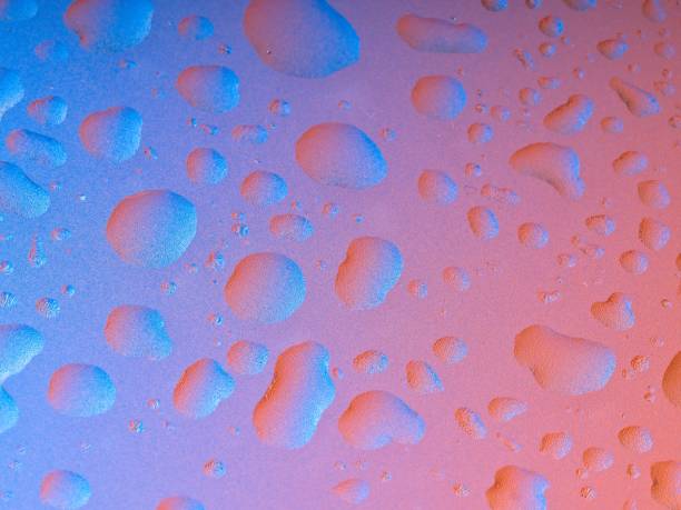 Blue and orange colored macro abstract background of water droplets on textured translucent sheet Blue and orange colored macro abstract background of water droplets on textured translucent sheet. Colorful light reflected and refracted through water drops with magnification. Metaphor for structure, thought, data, packets, and information storage. water thinking bubble drop stock pictures, royalty-free photos & images