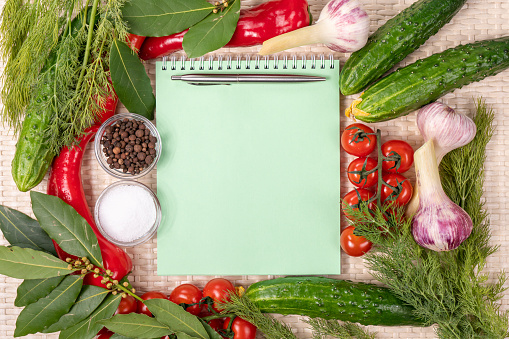 Empty space for copying the recipe book. View from above. Fresh vegetables, herbs, tomatoes and spices on a wicker wooden background. Recipe book with space for text.