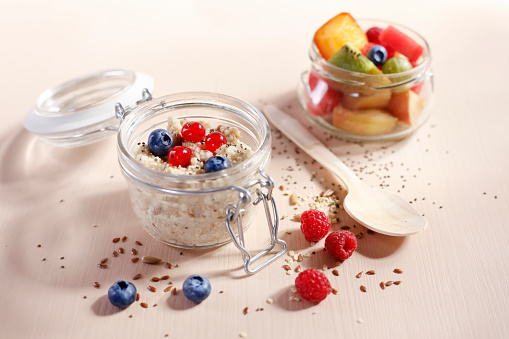 Fruit salad and porridge in a glass container with wooden spoon in the office