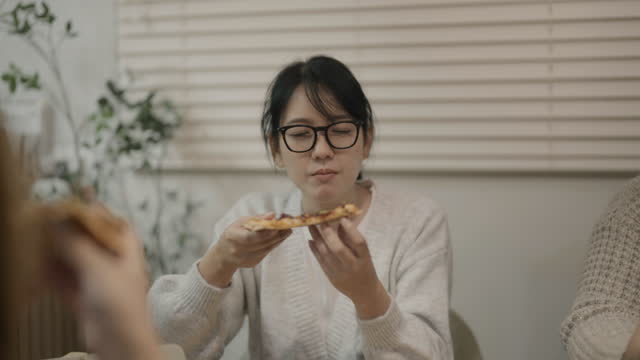 Asian friends group eating delicious pizza . Happy male and female friends are enjoying fast food.