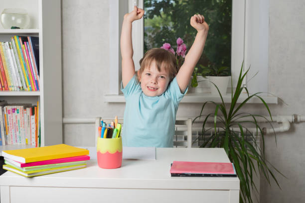 istock Relaxed smiling girl sits at the table, leans back in her chair and pulls her hands up. 1500642299