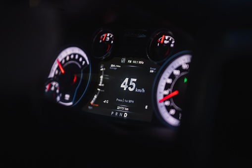 The dashboard of a sleek black car with bright white gauges and numbers