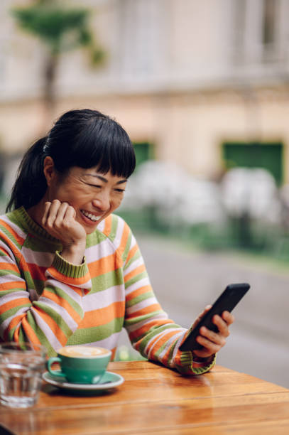 istock Smiling asian girl looking at her phone screen while having a video call. 1500651416