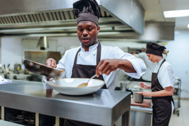 African-American chef finishing dish Young African-American chef finishing the spaghetti dish indoors restaurant hotel work tool stock pictures, royalty-free photos & images