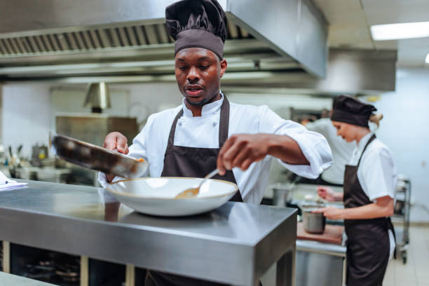 African-American chef finishing dish Young African-American chef finishing the spaghetti dish food service occupation stock pictures, royalty-free photos & images