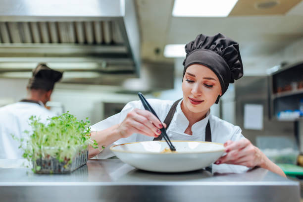 Young woman working as chef decorating plate