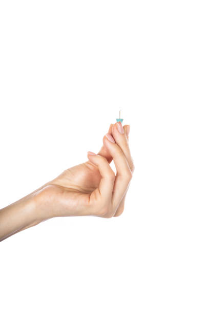 istock Push pins in hand isolated on white background. 1500658411