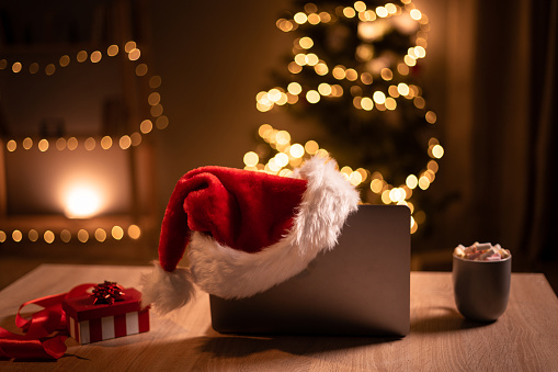 Laptop with Santa hat and christmas decoration on background. Copy space