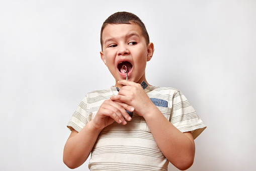 A 6-7 year old boy is angry holding a dental mirror. Concept of painful and unpleasant dental procedures.