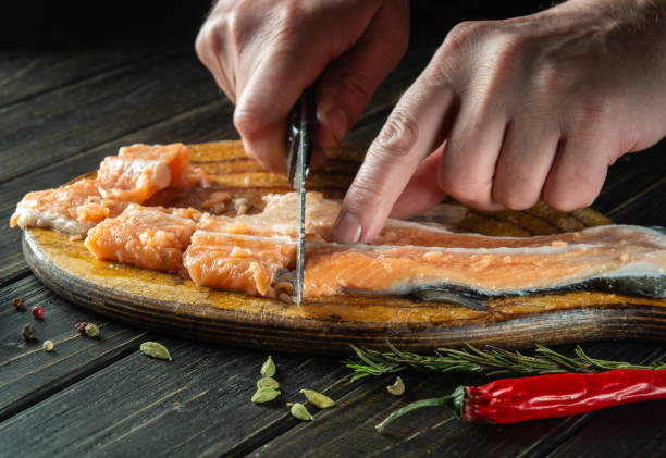 istock The cook cuts fresh red trout fish with a knife on a kitchen cutting board. Cooking a delicious fish dish according to an old recipe with spices 1500670139