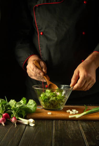 istock The chef mixes lettuce leaves in a bowl with a spoon. Working environment on a restaurant kitchen table. Delicious salad with fresh vegetables by the hands of the cook 1500670363