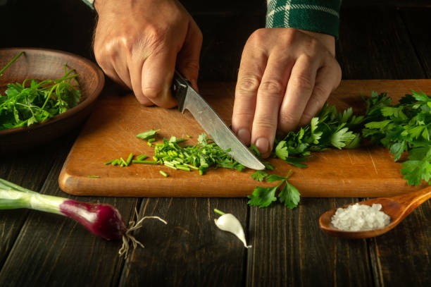 istock The cook cuts with a knife fresh parsley for salad on a kitchen board with fresh vegetables. The concept of cooking vegetable salad for a restaurant or cafe 1500670522