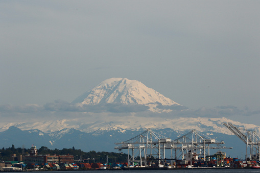 Mt. Rainier’s peak looks out above clouds and Seattle’s industrial waterfront
