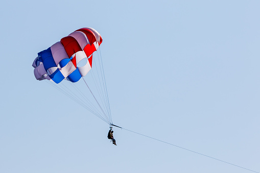 A patriotic red, white, and blue parachute over two parasailers enjoying leisure outdoors in Seattle