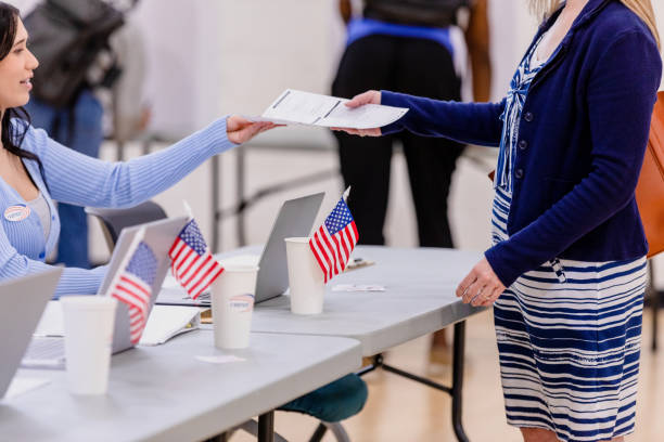 une jeune bénévole remet un bulletin de vote méconnaissable pour voter - election presidential candidate usa bipartisan photos et images de collection