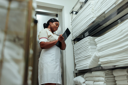 African-American hotel maid writing down numbers of clean sheets