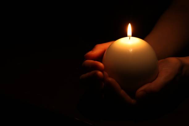 istock Woman holding burning candle in hands on black background, closeup. Space for text 1500683082