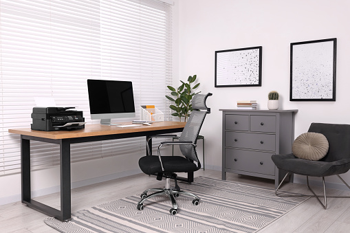 Stylish room interior with desk, modern printer and computer