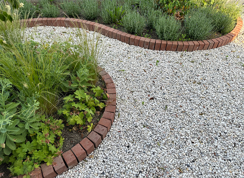 Front garden with light grey gravel. Flower beds and brick borders