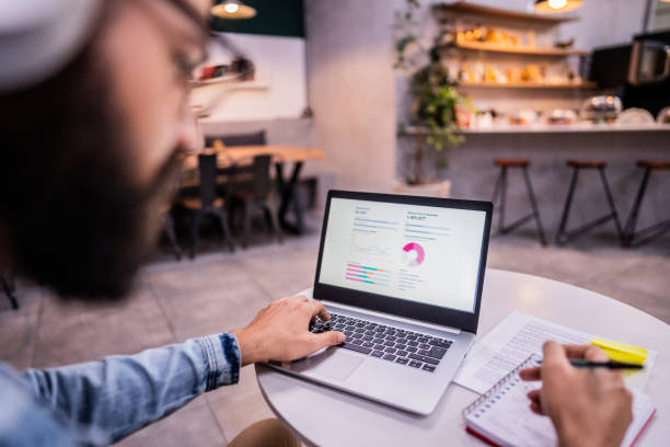 istock Close-up of man using the laptop analyzing financial graphs in a coffee shop 1500685224