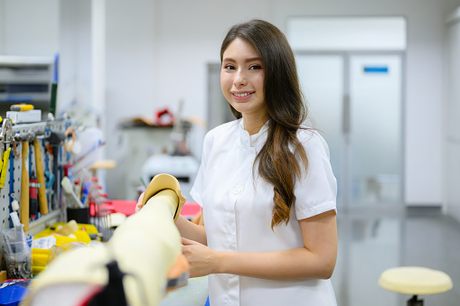 Female technician holding prosthetic limb checking and working in laboratory, Specialist with high tech technology at prosthetic manufacturing, New artificial limb production for disabled people