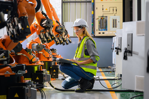 Female engineer worker working with robotic machine automation at factory, Female technician with smart technology at industry, Female worker checking and controlling parts of robotic machine