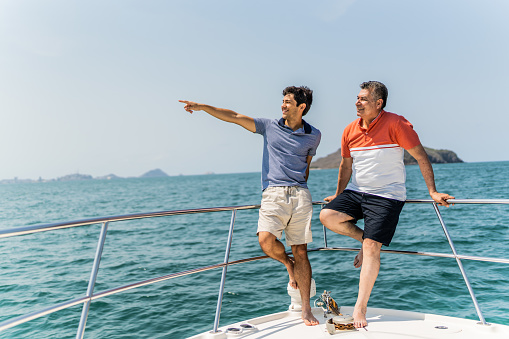 Father and son talking on boat deck during a yacht trip