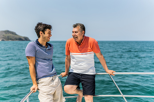 Father and son talking on boat deck during a yacht trip
