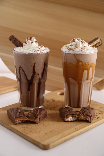 Milk shake blended with ice served with whip cream and chocolate sticks.
