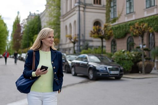 A business woman, casually dressed, walks through the streets of the city, in a good mood, smiling, talking on the phone and enjoying a sunny day.
Copy space, portrait.