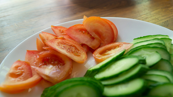 Chopped cucumbers. Chopped tomatoes. Sliced cucumbers and tomatoes on a plate