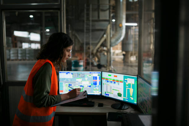 Female technician monitoring the production from the control room of wood factory stock photo