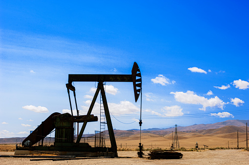 Cymric Oil Field pumpjack with hills and clouds in background.\n\nTaken in the Cymric Oil Field in Kern County, California, USA.