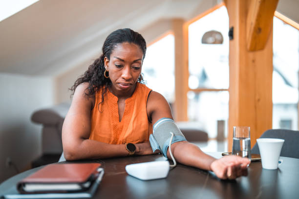 Black Female In 40s Using A Medical Device For Measuring Blood Pressure stock photo