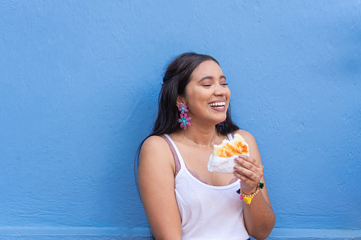 Latin woman having fun while eating street food