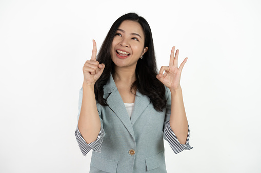 Portrait happy Asian woman shows ok sign and looking at the camera on white background.