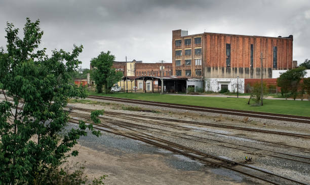 Meridian Train Depot Railroad tracks from the view of a bridge with a large industrial building on a stormy afternoon in Meridian, Mississippi meridian mississippi stock pictures, royalty-free photos & images