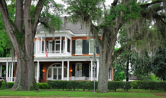 A historic mansion with a balcony and trees that have Spanish moss in Bainbridge, Georgia